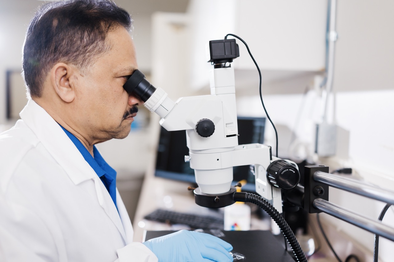 An Ultra Optics lab technician examines solutions under a microscope